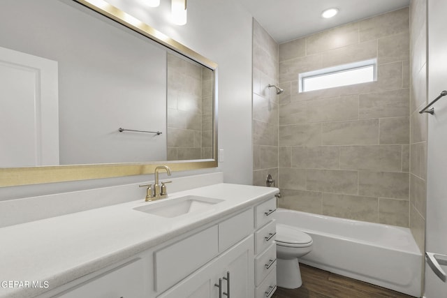 full bathroom featuring tiled shower / bath combo, toilet, wood-type flooring, and vanity