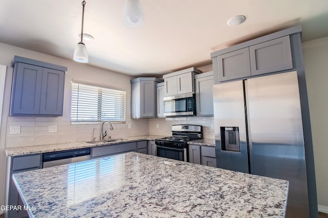 kitchen with sink, decorative backsplash, appliances with stainless steel finishes, decorative light fixtures, and light stone counters