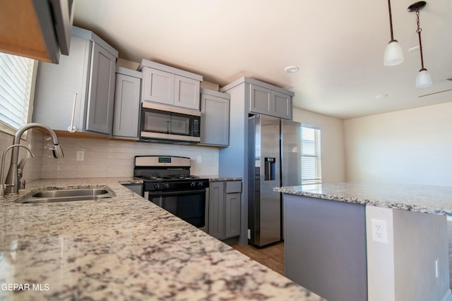 kitchen featuring gray cabinetry, backsplash, sink, decorative light fixtures, and stainless steel appliances