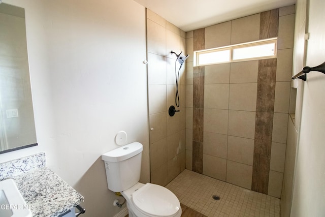 bathroom with vanity, toilet, and tiled shower