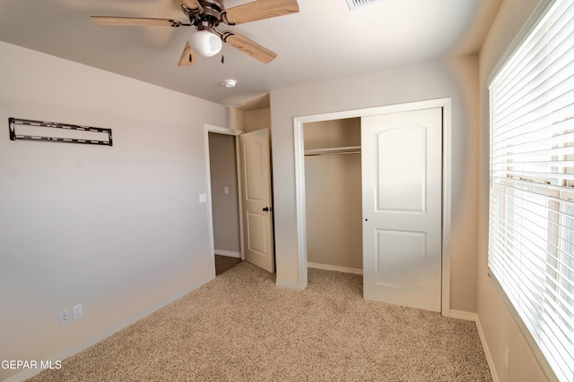 unfurnished bedroom featuring ceiling fan, light colored carpet, and a closet