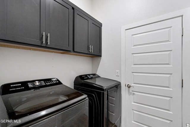 clothes washing area with washing machine and dryer and cabinets