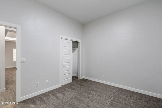 unfurnished bedroom featuring dark carpet, lofted ceiling, and a closet