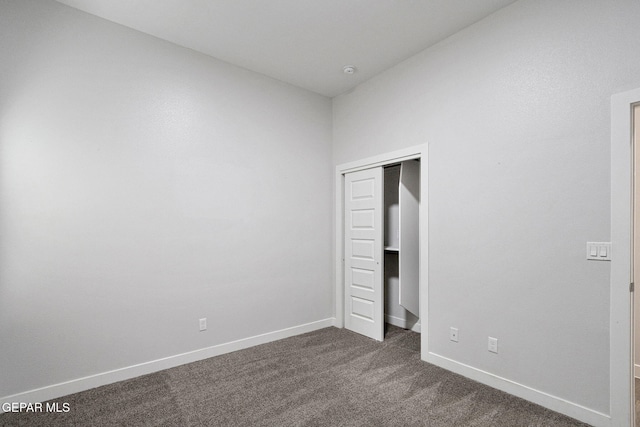 unfurnished bedroom featuring dark carpet and a closet