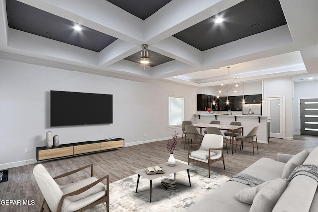 living room featuring a raised ceiling, light hardwood / wood-style flooring, and a notable chandelier