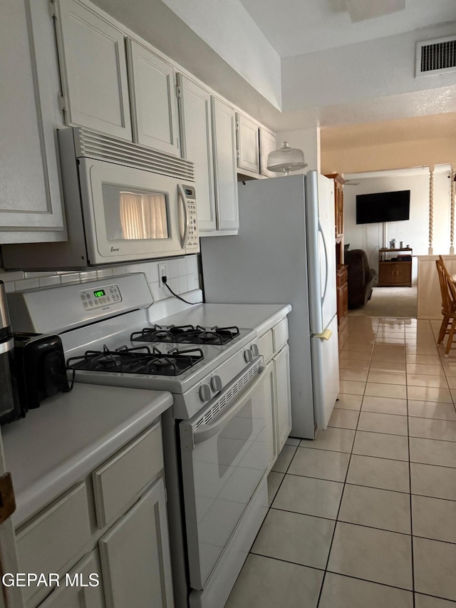 kitchen with white cabinets, light tile patterned flooring, and white appliances