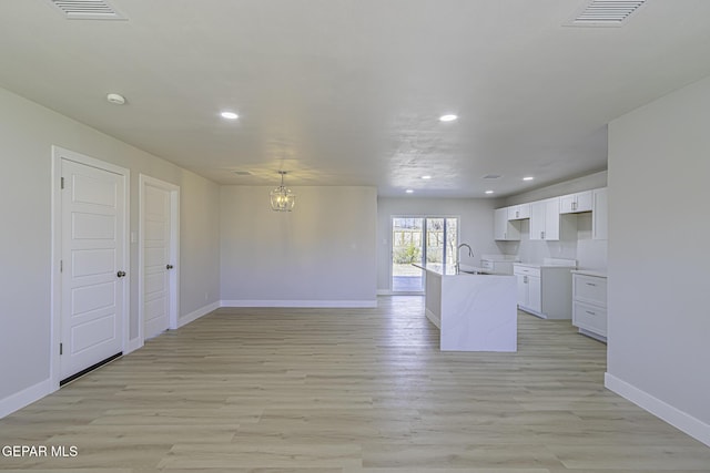 kitchen with sink, an inviting chandelier, light hardwood / wood-style floors, white cabinetry, and hanging light fixtures