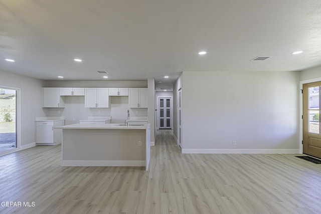 kitchen featuring white cabinetry, a kitchen island with sink, sink, and light hardwood / wood-style floors