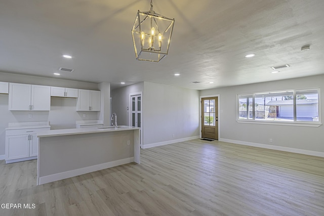 kitchen featuring white cabinetry, a kitchen island with sink, decorative light fixtures, and an inviting chandelier