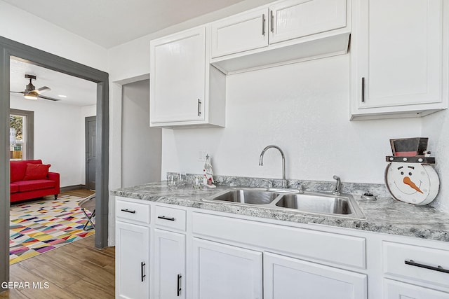 kitchen with hardwood / wood-style flooring, white cabinetry, ceiling fan, and sink