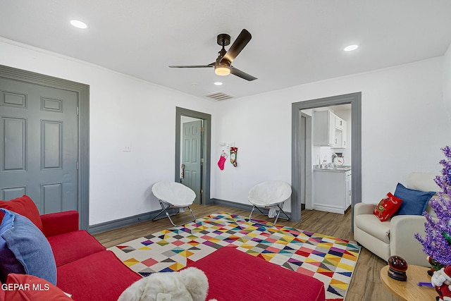 living room featuring light hardwood / wood-style floors, ceiling fan, and ornamental molding