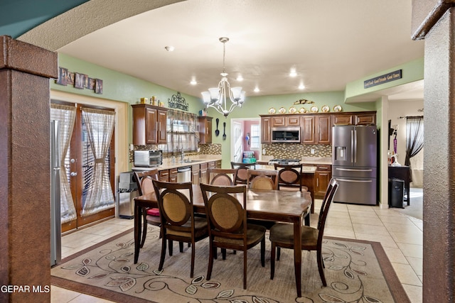 tiled dining space featuring plenty of natural light, a chandelier, and sink