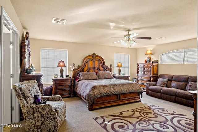 carpeted bedroom with ceiling fan and a textured ceiling