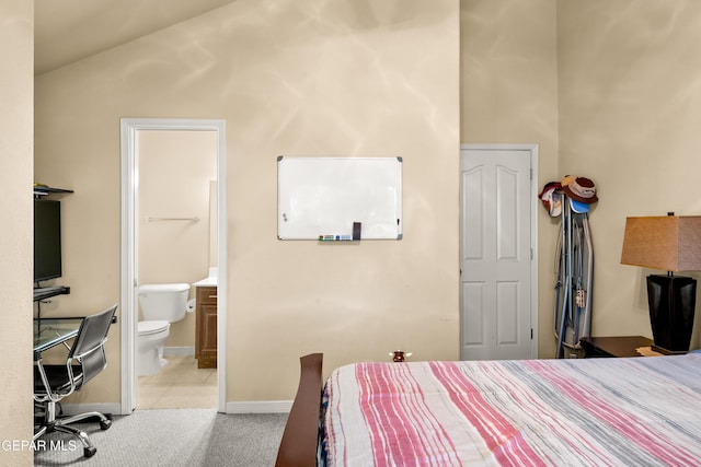 bedroom featuring ensuite bath, light carpet, and vaulted ceiling