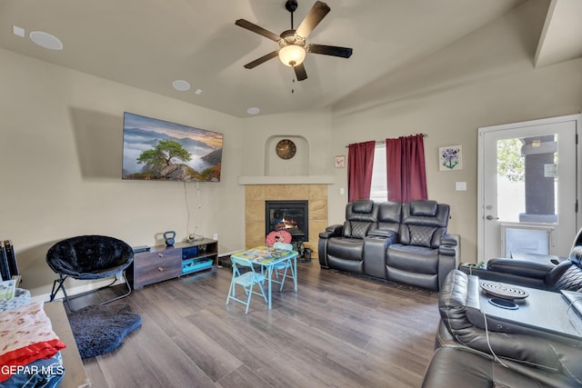 living room featuring ceiling fan, a tile fireplace, and hardwood / wood-style flooring