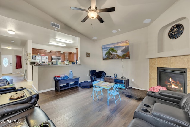 living room with ceiling fan, a tile fireplace, light hardwood / wood-style flooring, and lofted ceiling