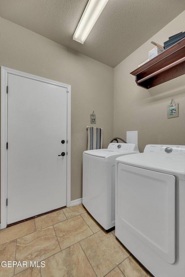 laundry area featuring a textured ceiling and washer and clothes dryer