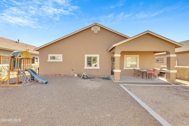 rear view of property with a patio and a playground