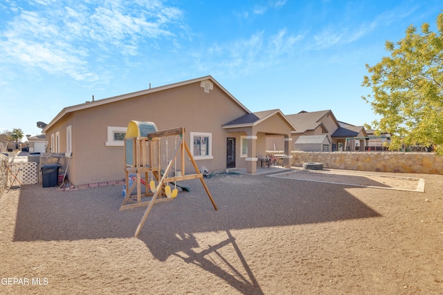 rear view of property with a playground and a patio