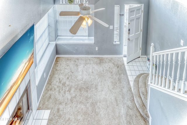 carpeted spare room featuring a ceiling fan, tile patterned flooring, a textured wall, and baseboards