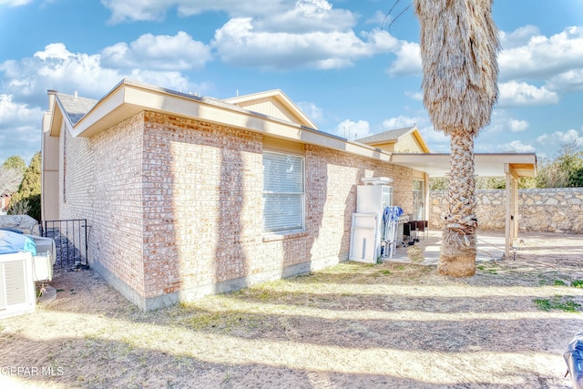 view of home's exterior with brick siding, a patio area, and fence