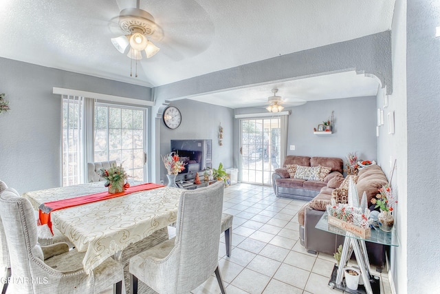 dining area with light tile patterned floors, ceiling fan, arched walkways, and a textured ceiling