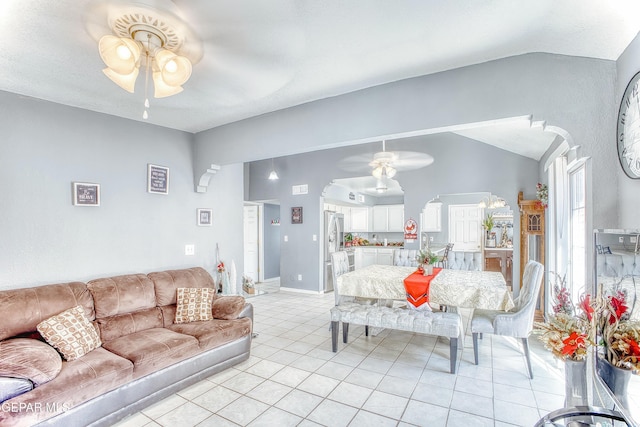 living area featuring light tile patterned floors, arched walkways, a ceiling fan, baseboards, and vaulted ceiling