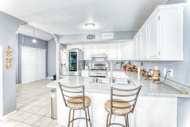 kitchen featuring visible vents, appliances with stainless steel finishes, a peninsula, under cabinet range hood, and a sink