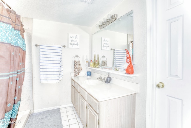 full bath with a textured ceiling, a shower with shower curtain, vanity, baseboards, and tile patterned floors