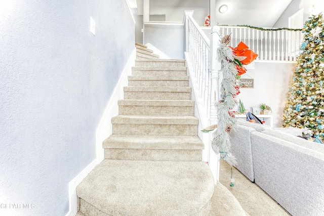 staircase featuring a textured wall and carpet floors