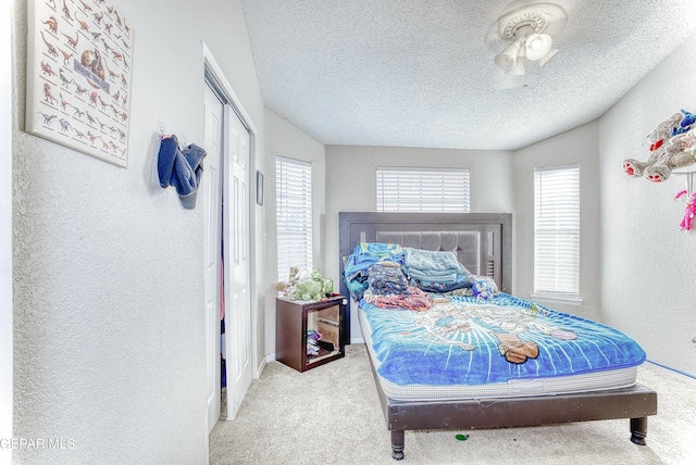 carpeted bedroom featuring a closet, a textured wall, and a textured ceiling