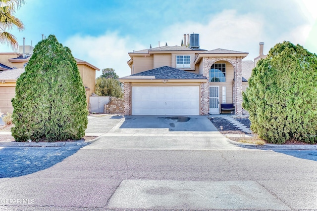 traditional-style home with concrete driveway, brick siding, an attached garage, and central air condition unit