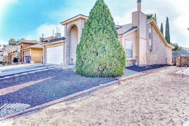 view of front of property with driveway, a chimney, and an attached garage