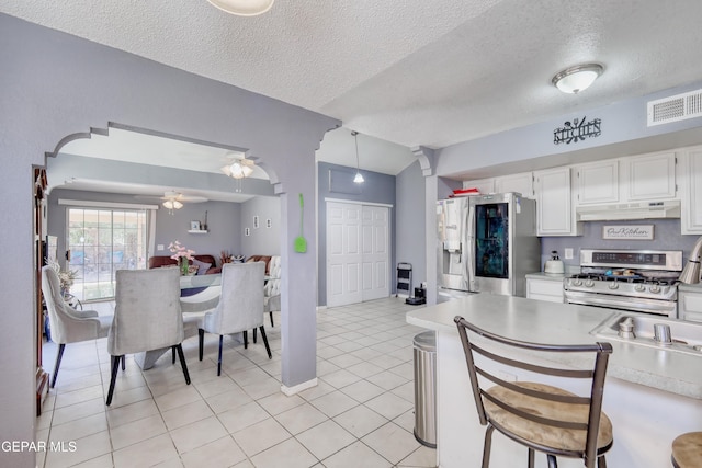 11948 Mcauliffe Dr, El Paso, TX 79936 - kitchen with stainless steel appliances, under cabinet range hood, light countertops, white cabinets, and a textured ceiling
