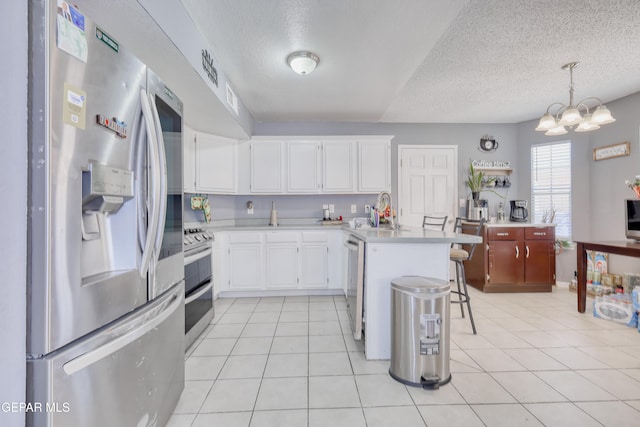 11948 Mcauliffe Dr, El Paso, TX 79936 - kitchen featuring stainless steel appliances, a peninsula, light countertops, a textured ceiling, and white cabinets