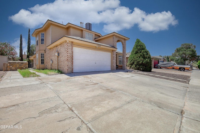 11948 Mcauliffe Dr, El Paso, TX 79936 - view of front of property featuring brick siding, a garage, driveway, and cooling unit