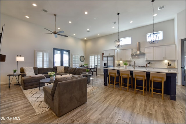 living room featuring ceiling fan with notable chandelier, a towering ceiling, and sink