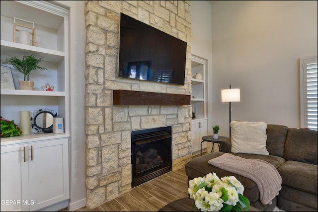 living room featuring built in features and a stone fireplace