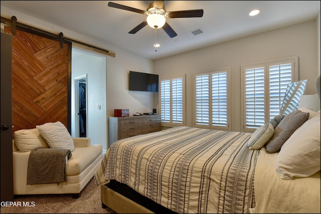 carpeted bedroom featuring a barn door and ceiling fan