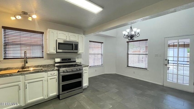 kitchen with sink, hanging light fixtures, a notable chandelier, white cabinets, and appliances with stainless steel finishes