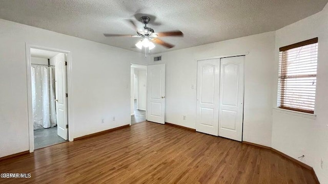 unfurnished bedroom with ceiling fan, a closet, a textured ceiling, and hardwood / wood-style flooring