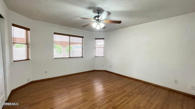 unfurnished room featuring ceiling fan, a healthy amount of sunlight, a textured ceiling, and wood-type flooring