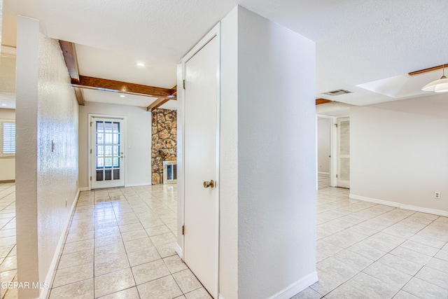 corridor with beam ceiling, light tile patterned flooring, and a textured ceiling