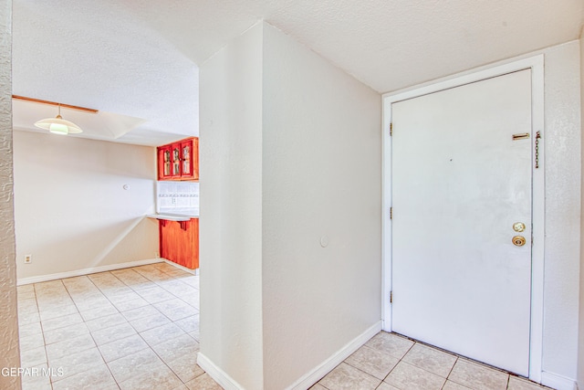 foyer with a textured ceiling and light tile patterned flooring