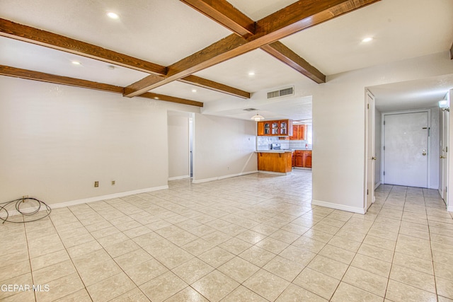 unfurnished living room with beamed ceiling and light tile patterned floors