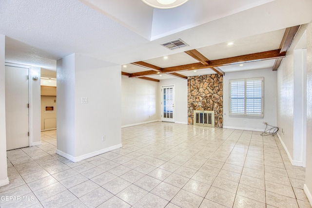 unfurnished living room with beamed ceiling, light tile patterned floors, a textured ceiling, and a stone fireplace