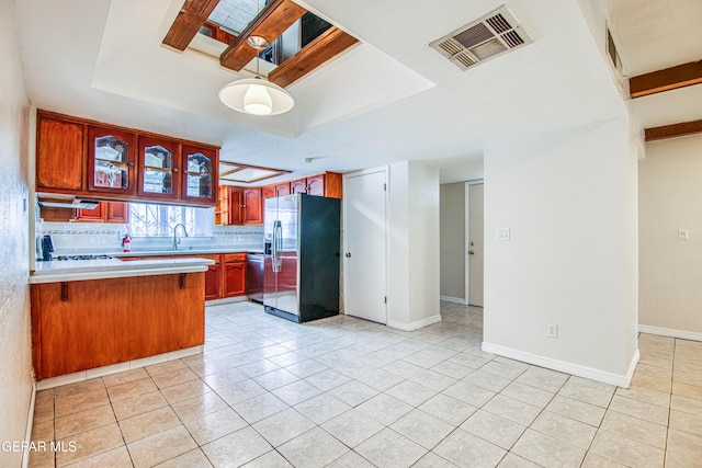 kitchen featuring sink, kitchen peninsula, decorative backsplash, light tile patterned floors, and appliances with stainless steel finishes