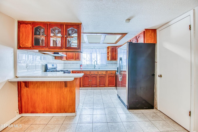 kitchen with kitchen peninsula, refrigerator, sink, electric stove, and a breakfast bar area