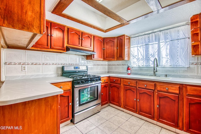 kitchen featuring backsplash, light tile patterned floors, sink, and stainless steel gas range