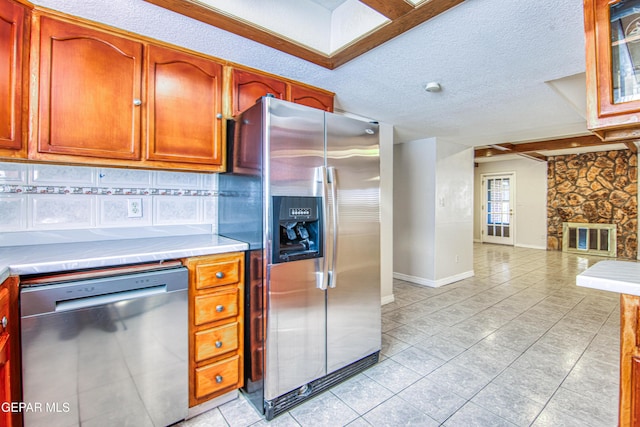 kitchen featuring decorative backsplash, stainless steel appliances, and a textured ceiling